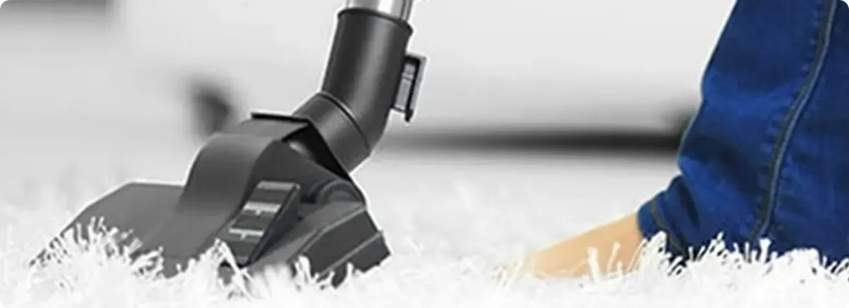 Close-up of a professional vacuuming a white carpet in Rochdale.